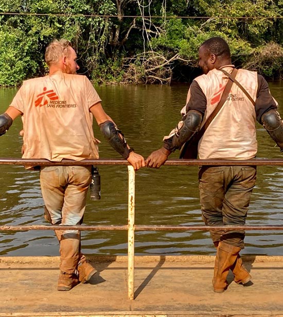 2 membres du staff MSF, vus de dos, vêtus d'un T-shirt blanc avec logo MSF