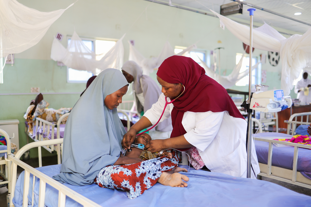 Une médecin de MSF examine Abubakar Gharzali, l'enfant de sept mois de Faiza Isa, au centre nutritionnel thérapeutique pour patients hospitalisés d'Unguwa Uku, soutenu par MSF, dans la zone de gouvernement local de Taruni, dans l'État de Kano. Nigeria, juin 2026 ©Abba Adamu Musa/MSF