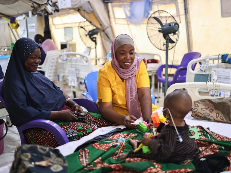 Maryam Alimu, conseillère et formatrice pour MSF, anime une séance de thérapie par le jeu avec Aisha Abdulkareem, la fille de sept mois de Latifat Abdulkareem, hospitalisée et soignée pour malnutrition au centre MSF Nilefa Kiji, à Maiduguri, dans l'État de Borno, au nord-est du Nigeria. Nigéria, novembre 2025 ©Abba Adamu Musa/MSF