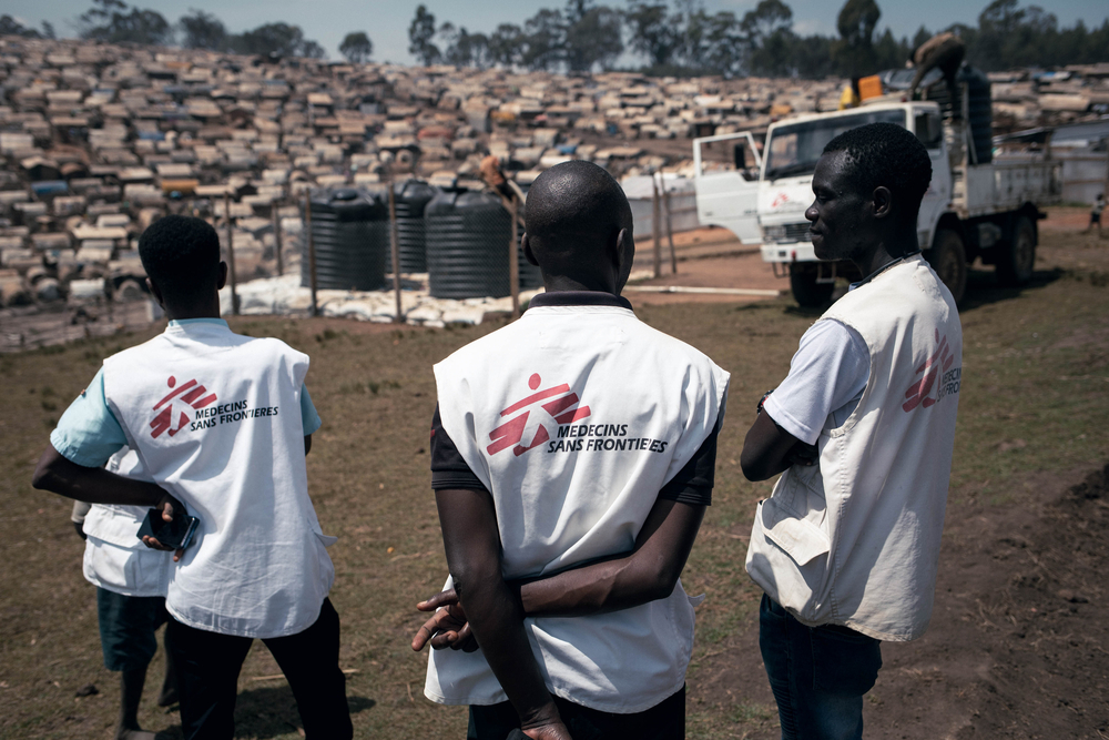 Une équipe MSF Eau et Assainissement supervise le transbordement d'eau d'un camion vers des réservoirs alimentant un point de distribution, dans le camp de Plaine Savo (visible en arrière-plan), qui abrite environ 76 000 personnes déplacées.