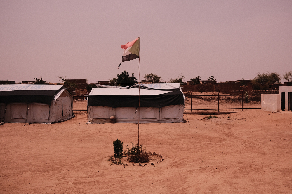 Un drapeau soudanais déchiré flotte au-dessus d'un centre de soins de santé primaires fermé dans le camp de déplacés de Hashayisa, à Zalingei. Les coupes budgétaires dans l'aide humanitaire internationale ont entraîné la fermeture et le dysfonctionnement des centres de soins de santé primaires sur lesquels les déplacés et les communautés d'accueil du Darfour comptaient auparavant.