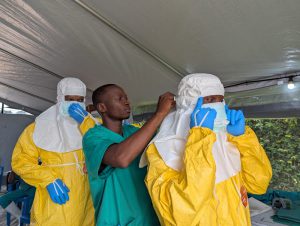 Le personnel du centre de traitement Ebola de l’Hôpital du Cinquantenaire, à Kisangani, aide ses collègues à revêtir leur équipement de protection individuelle (EPI) avant de pénétrer dans la zone à haut risque. RDC, Août 2026 ©Belen Filgueira/MSF