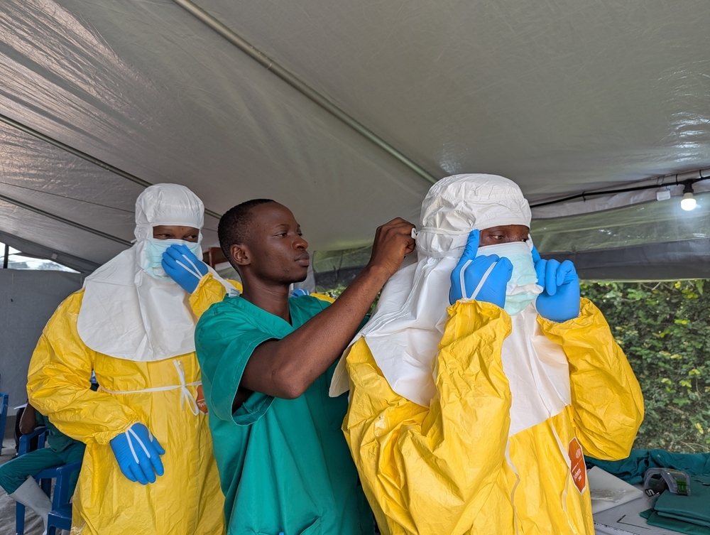 Le personnel du centre de traitement Ebola de l’Hôpital du Cinquantenaire, à Kisangani, aide ses collègues à revêtir leur équipement de protection individuelle (EPI) avant de pénétrer dans la zone à haut risque. RDC, Août 2026 ©Belen Filgueira/MSF