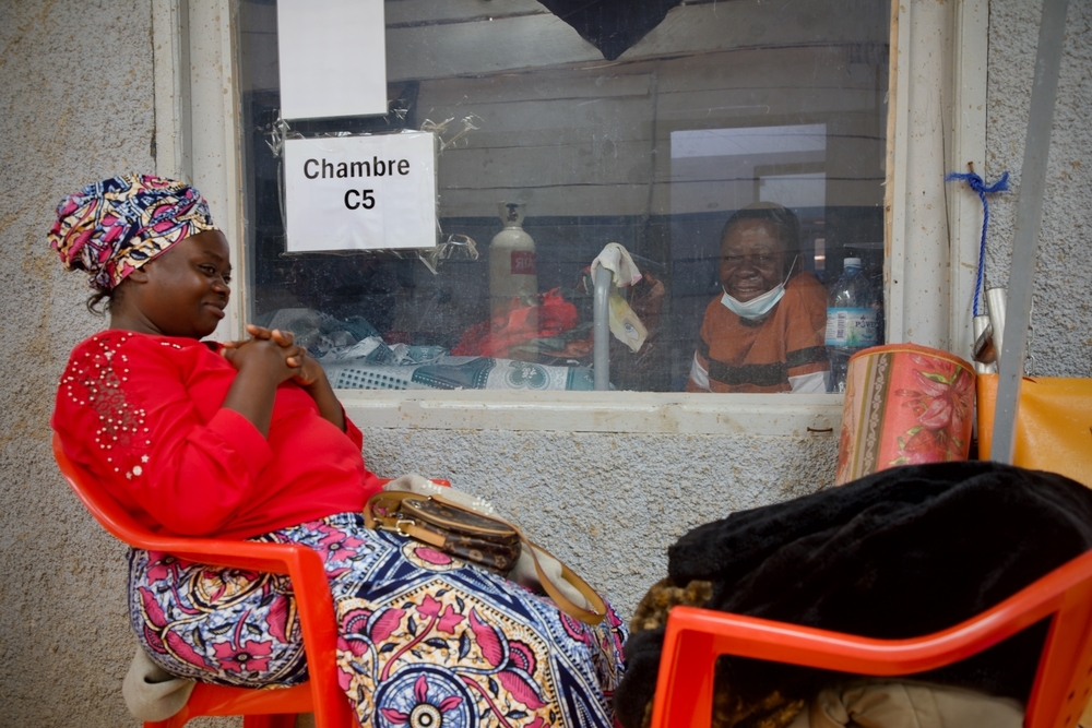 Comme elle le fait chaque jour depuis 13 jours — soit depuis l’hospitalisation de son mari, Victoire —, Kasoki a l’intention de rester à ses côtés de 6 h 30 à 18 h 30. Kasoki observe son mari de l’autre côté de la vitre et lui apporte son soutien, alors que son état de santé montre des signes d’amélioration. RDC, Butembo, Octobre 2026 ©Elio Parfait/MSF