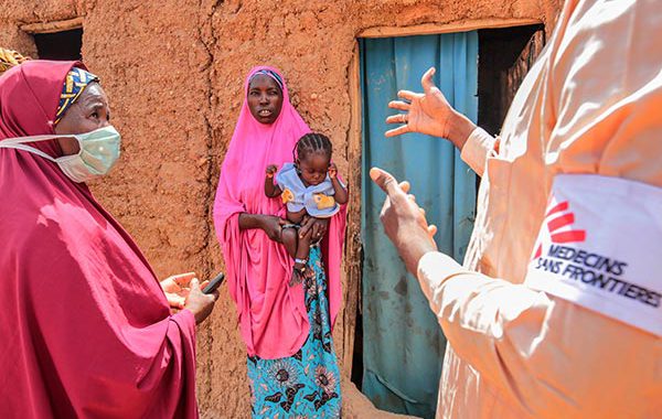 Discussion entre un membre du staff de MSF avec brassard MSF sur l'avant-bras, et 2 femmes